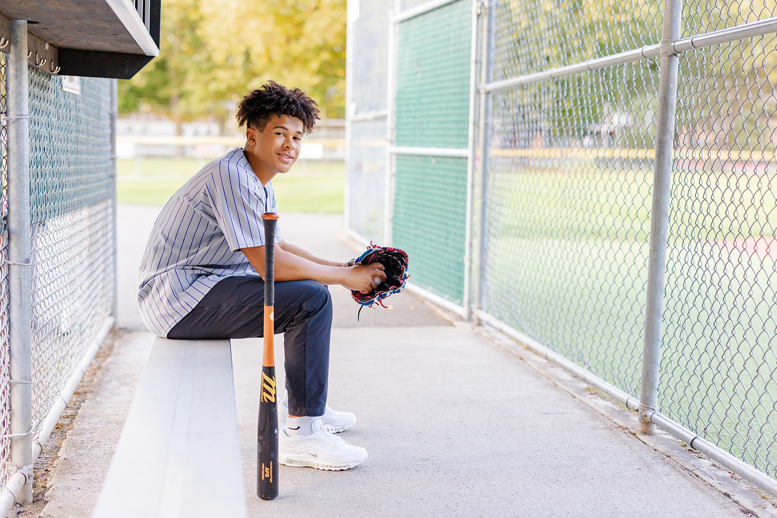 A high school baseball player sits on the dugout bench with his glove and ball after exploring volunteer opportunities in Issaquah
