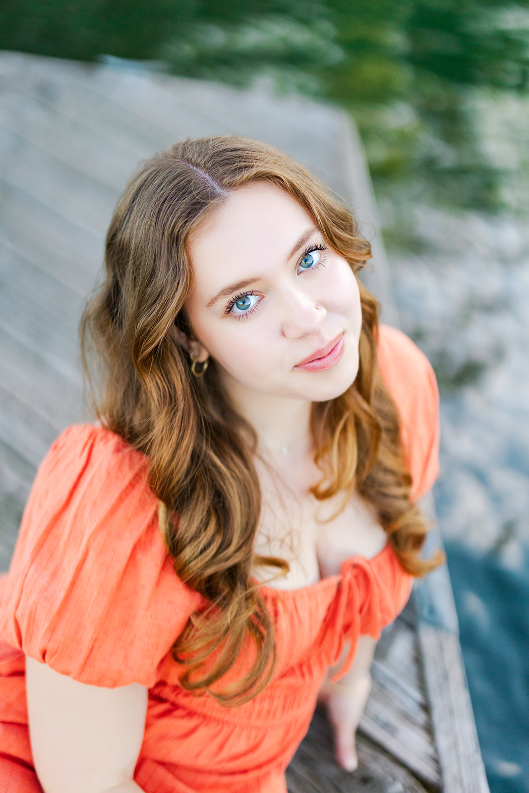 A high school senior in a red dress sits on a wooden dock after exploring volunteer opportunities in Kirkland