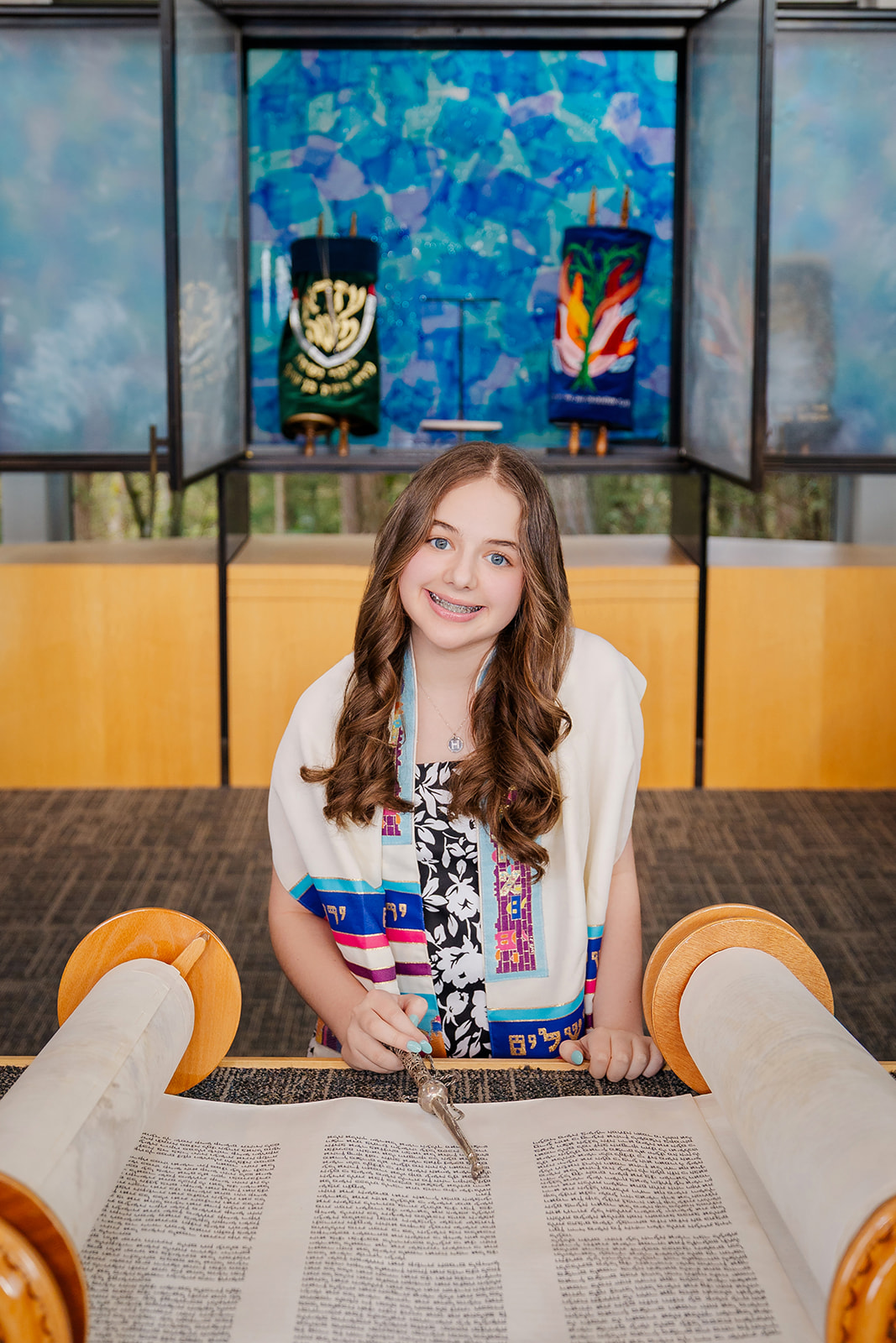 A teen girl smiles big while reading from the torah before her bat mitvah